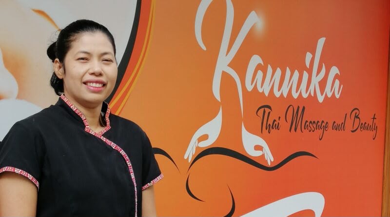 Kannika, the owner, smiling in front of the studio's orange Kannika sign